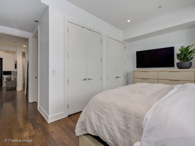 bedroom with dark hardwood / wood-style flooring and multiple closets