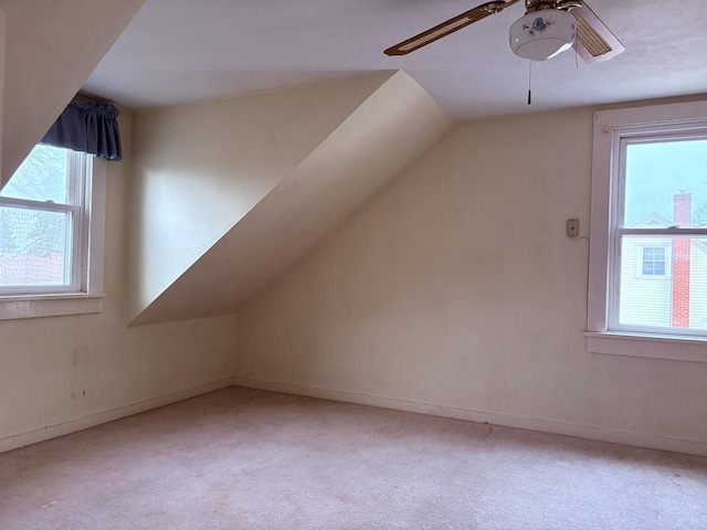 additional living space with light carpet, a wealth of natural light, and ceiling fan