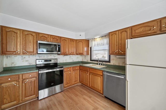 kitchen featuring backsplash, sink, appliances with stainless steel finishes, and light hardwood / wood-style flooring