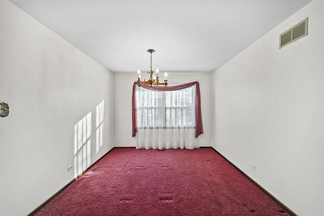 carpeted empty room with a notable chandelier