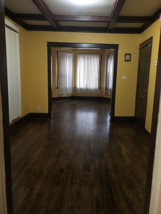 empty room with beam ceiling, dark hardwood / wood-style flooring, and coffered ceiling