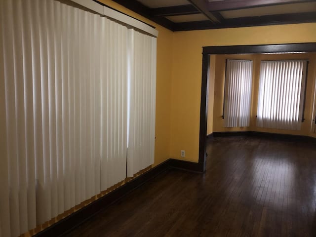 spare room with beamed ceiling, dark hardwood / wood-style floors, and coffered ceiling