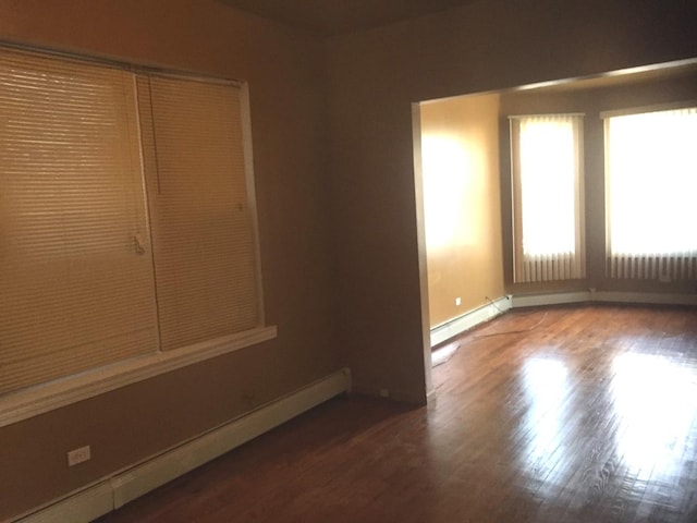 unfurnished room with wood-type flooring and a baseboard radiator