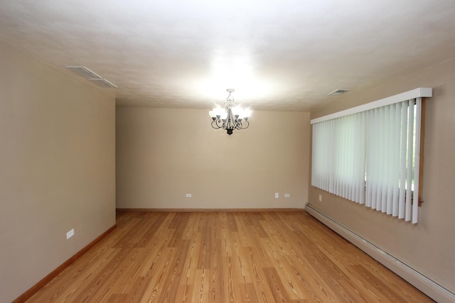 empty room featuring light wood-type flooring, an inviting chandelier, and baseboard heating