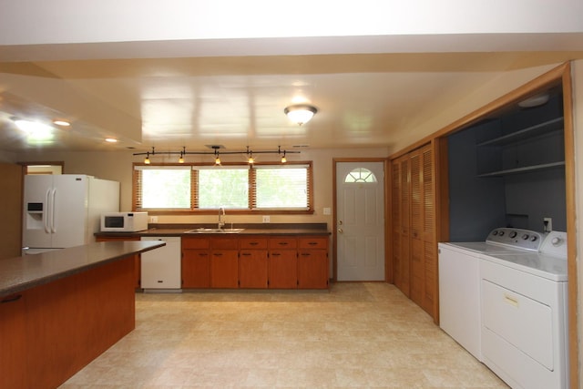 kitchen featuring washing machine and clothes dryer, sink, and white appliances