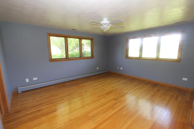 spare room featuring ceiling fan, light wood-type flooring, and a baseboard heating unit