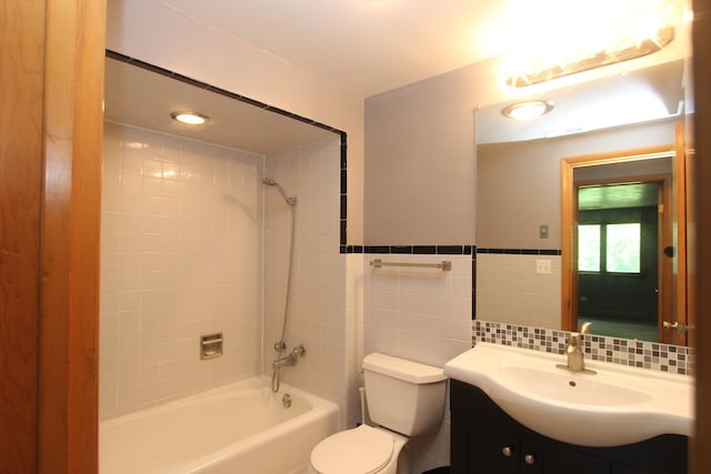 full bathroom featuring toilet, decorative backsplash, vanity, tile walls, and tiled shower / bath