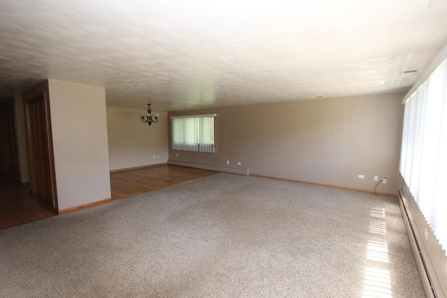 unfurnished room with carpet flooring, a chandelier, a baseboard radiator, and a textured ceiling