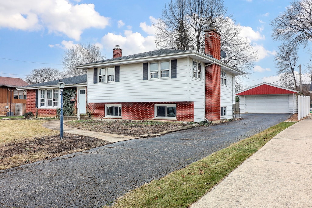 tri-level home with central AC unit, a garage, and an outdoor structure