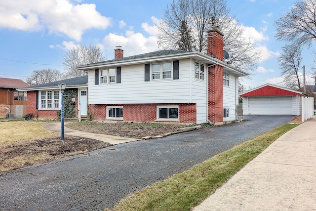 tri-level home with central AC unit, a garage, and an outdoor structure