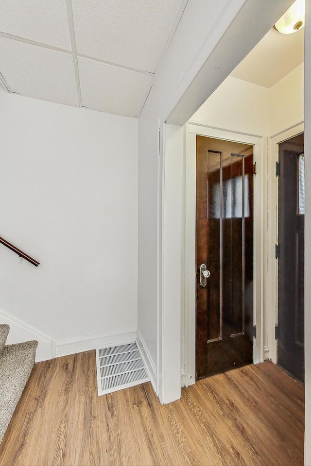 hall with a drop ceiling and light wood-type flooring