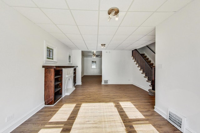 unfurnished living room featuring hardwood / wood-style flooring, ceiling fan, and a paneled ceiling