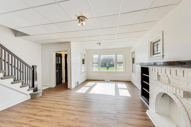 unfurnished living room featuring wood-type flooring and a drop ceiling