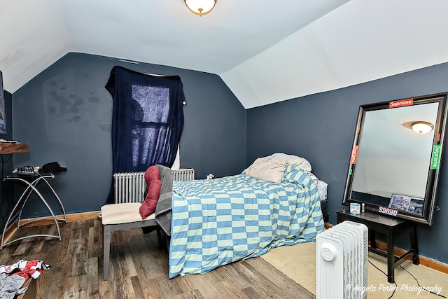 bedroom with wood-type flooring, radiator, and vaulted ceiling