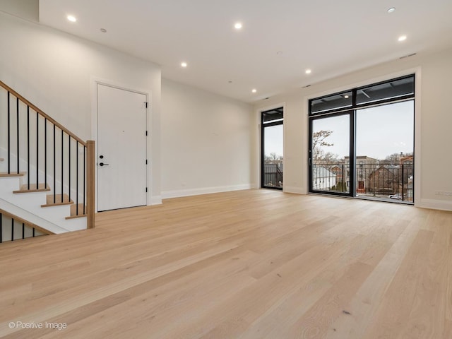 unfurnished room with light hardwood / wood-style floors and a wall of windows