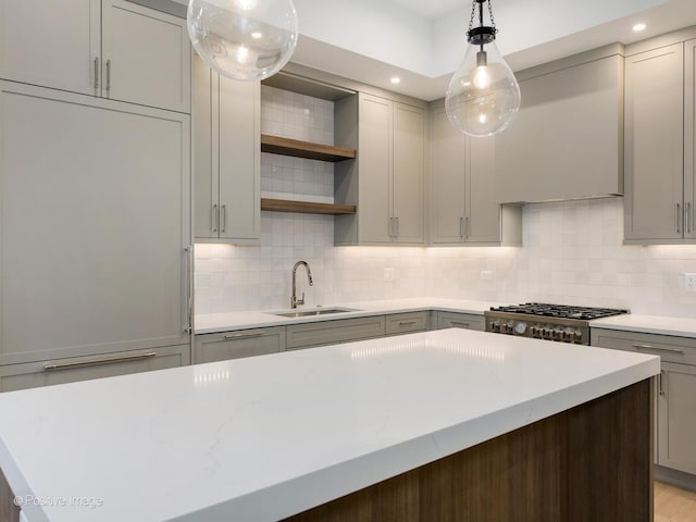 kitchen with light stone countertops, sink, a center island, decorative light fixtures, and range