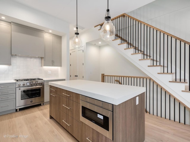 kitchen with high end stove, gray cabinets, a center island, and light hardwood / wood-style floors