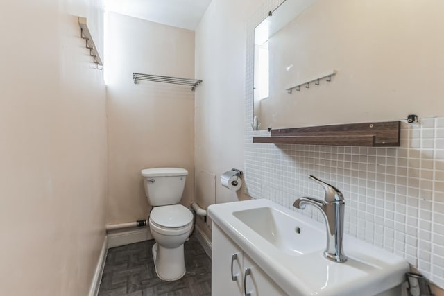 bathroom with decorative backsplash, toilet, vanity, and parquet flooring