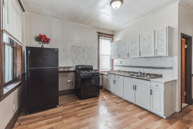 kitchen with backsplash, sink, black appliances, light hardwood / wood-style floors, and white cabinetry