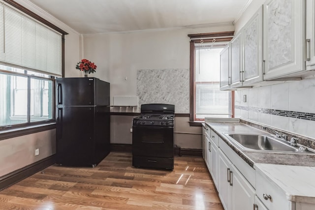 kitchen featuring crown molding, sink, black appliances, hardwood / wood-style floors, and white cabinetry