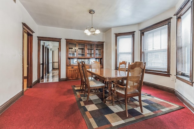 carpeted dining area with an inviting chandelier