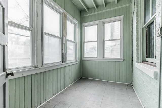 unfurnished sunroom featuring beamed ceiling