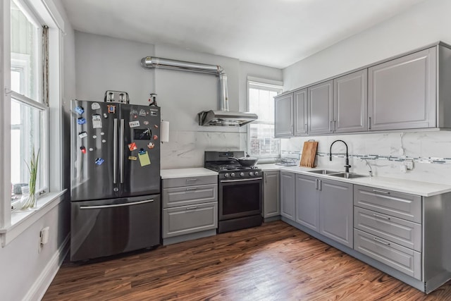 kitchen featuring backsplash, sink, gas range, gray cabinets, and stainless steel refrigerator