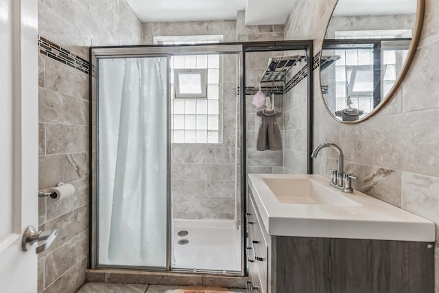 bathroom featuring a healthy amount of sunlight, a shower with shower door, and tile walls