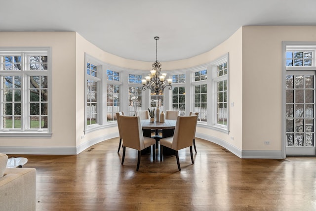 dining room with a wealth of natural light, dark hardwood / wood-style floors, and a notable chandelier