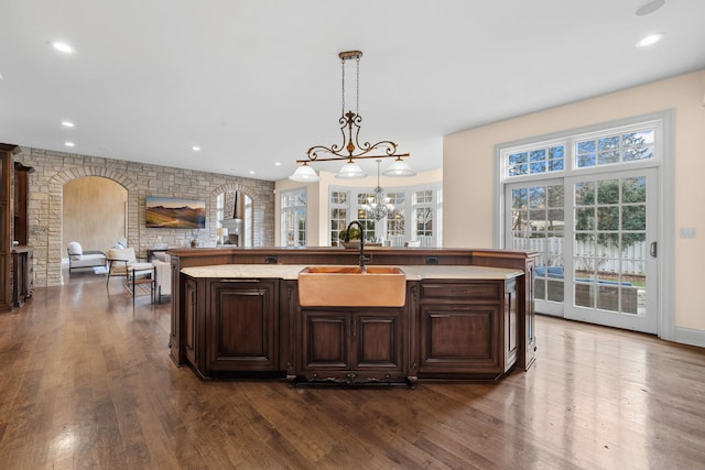 kitchen featuring dark brown cabinetry, sink, an island with sink, and decorative light fixtures