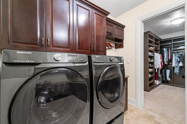 clothes washing area with washer and clothes dryer, light colored carpet, and cabinets