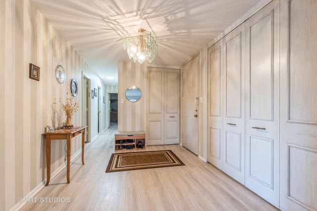 hall with light hardwood / wood-style floors and an inviting chandelier