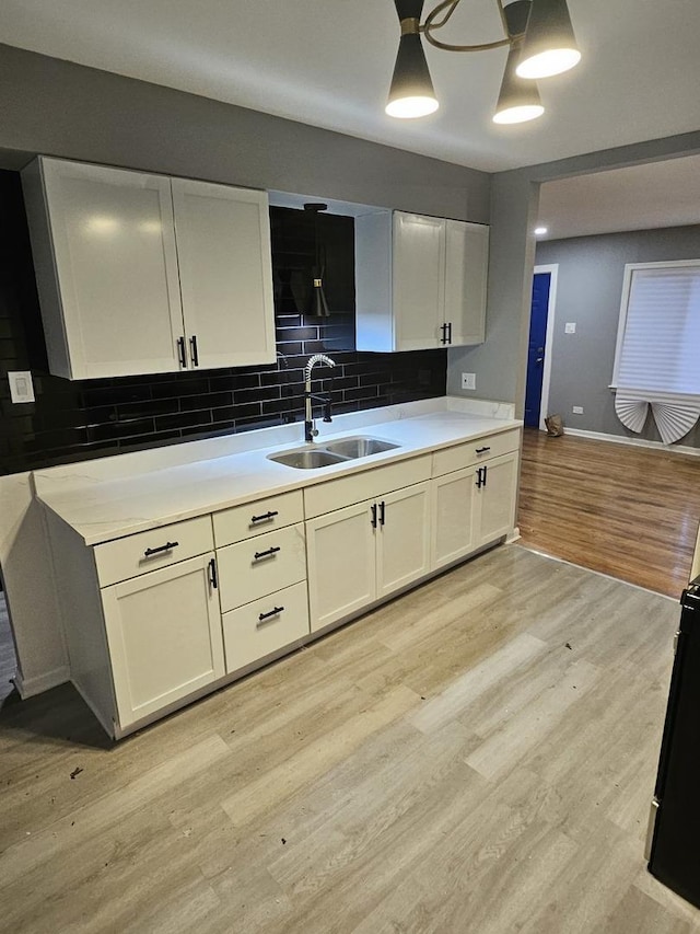 kitchen with backsplash, sink, decorative light fixtures, light hardwood / wood-style floors, and white cabinetry