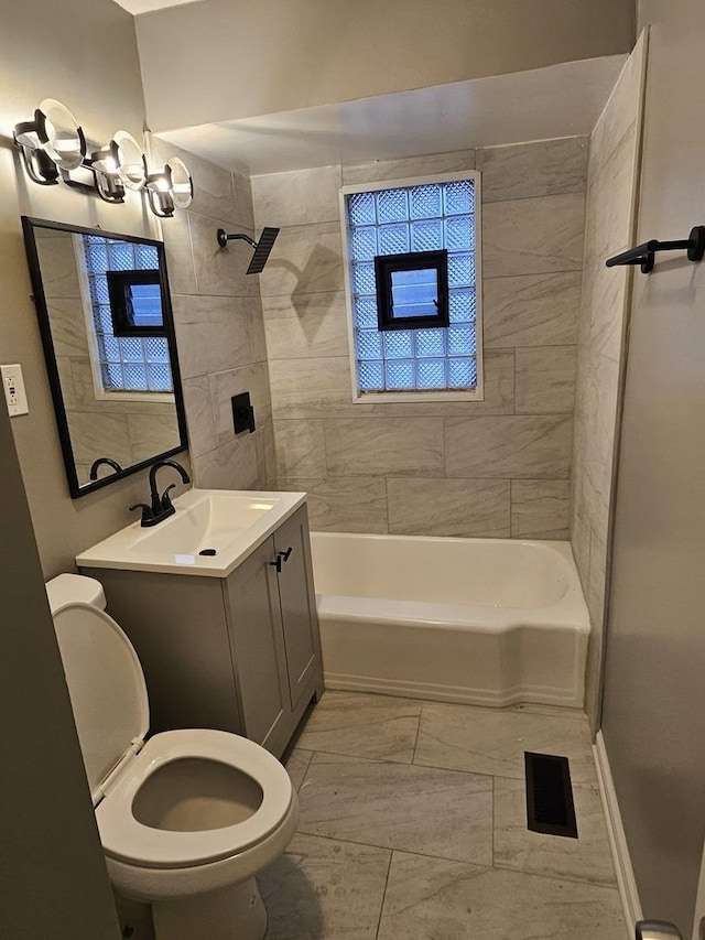 full bathroom with toilet, vanity, and tiled shower / bath