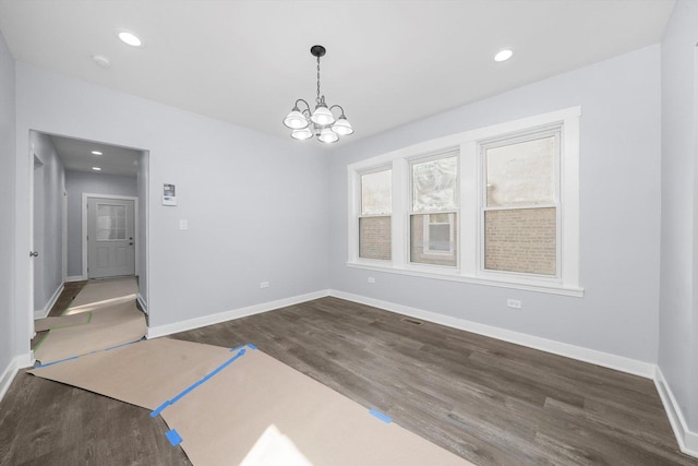 unfurnished room featuring an inviting chandelier and dark wood-type flooring