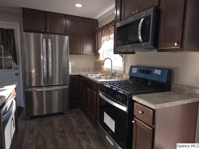 kitchen with sink, dark hardwood / wood-style flooring, stainless steel appliances, crown molding, and dark brown cabinets