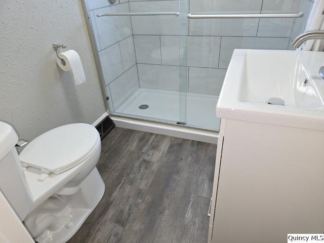 bathroom featuring walk in shower, hardwood / wood-style floors, vanity, and toilet