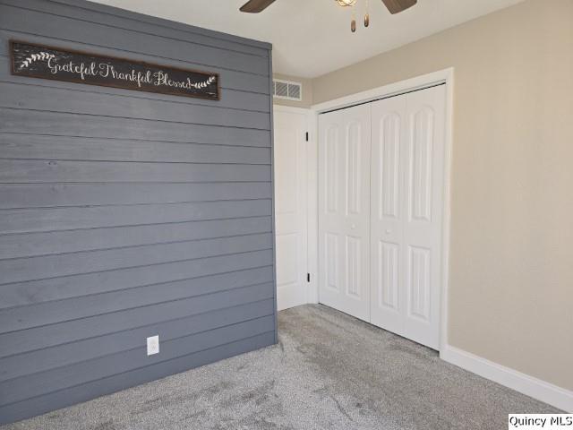 interior space with carpet floors, ceiling fan, and a closet