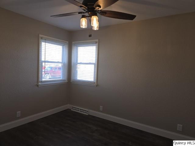 spare room with dark hardwood / wood-style floors and ceiling fan