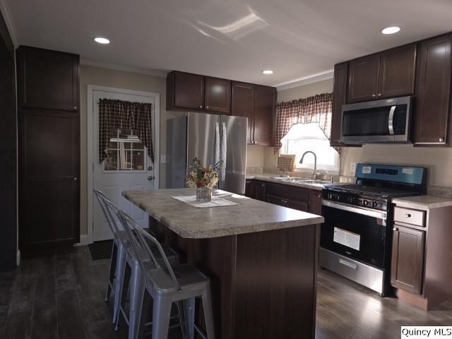 kitchen with sink, a center island, dark brown cabinets, dark hardwood / wood-style floors, and stainless steel appliances