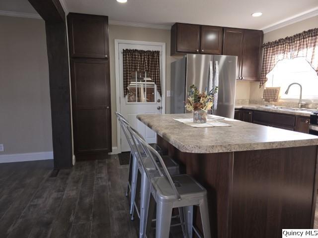 kitchen featuring sink, stainless steel fridge, a kitchen bar, a center island, and dark brown cabinetry