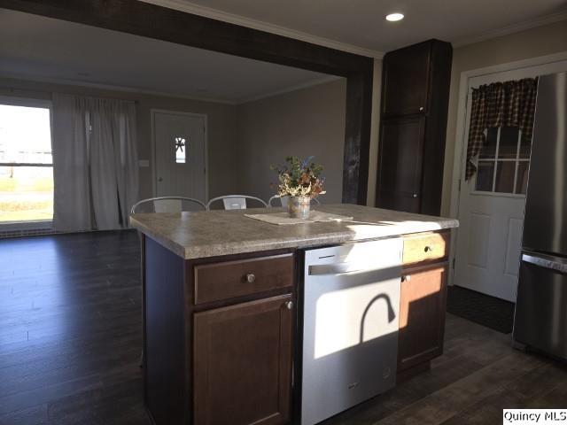 kitchen with crown molding, a kitchen island, dark hardwood / wood-style floors, and stainless steel refrigerator