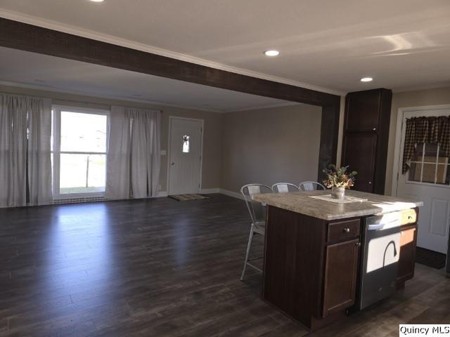 kitchen with a breakfast bar, ornamental molding, dark hardwood / wood-style flooring, and a center island