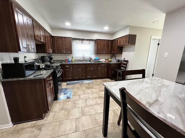 kitchen with light stone counters, sink, stainless steel stove, and dark brown cabinets