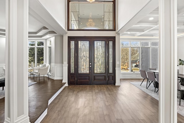 foyer entrance featuring coffered ceiling, hardwood / wood-style floors, beam ceiling, and a high ceiling