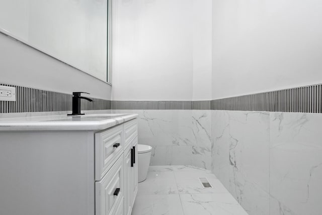 bathroom featuring vanity, tile walls, and toilet