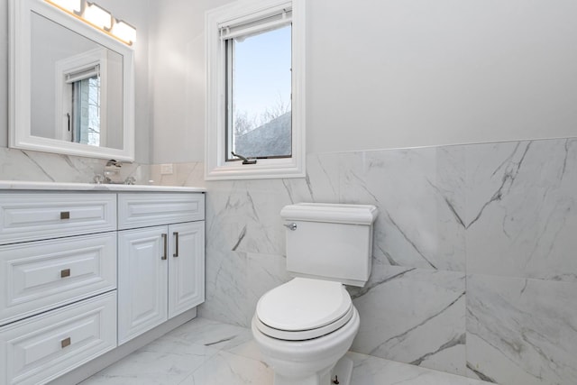 bathroom with vanity, tile walls, and toilet