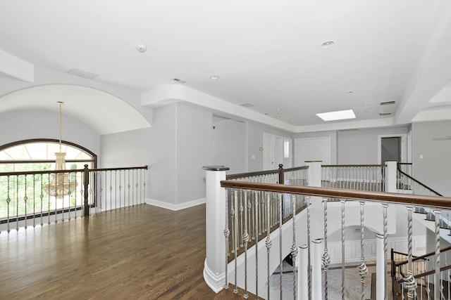 hall with dark hardwood / wood-style floors and a chandelier