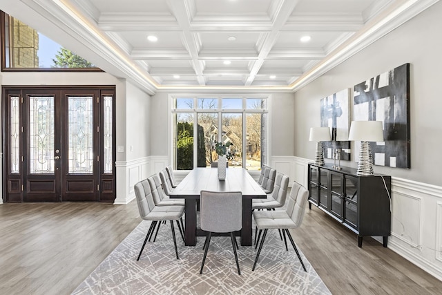 dining area with beamed ceiling, coffered ceiling, wood-type flooring, and a healthy amount of sunlight