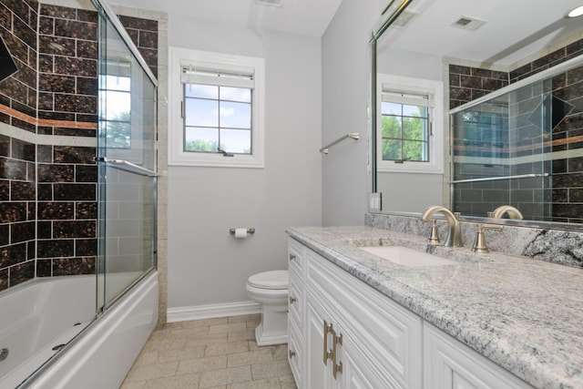 full bathroom with enclosed tub / shower combo, vanity, and toilet